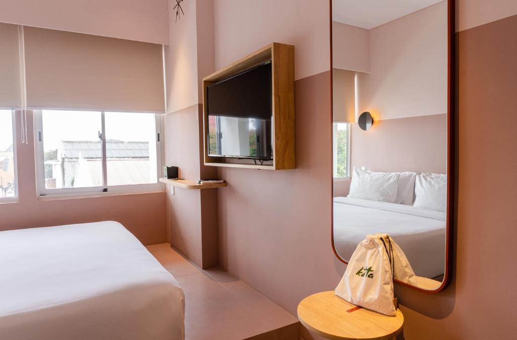 a hotel room with two beds and a mirror at Kotta Hotel Semarang in Semarang