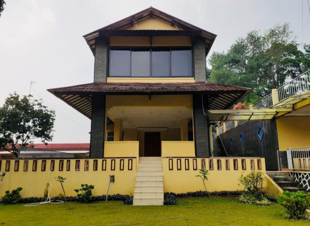 a house with a yellow facade with a large window at Villa Mawar Bumi Citeko in Bogor