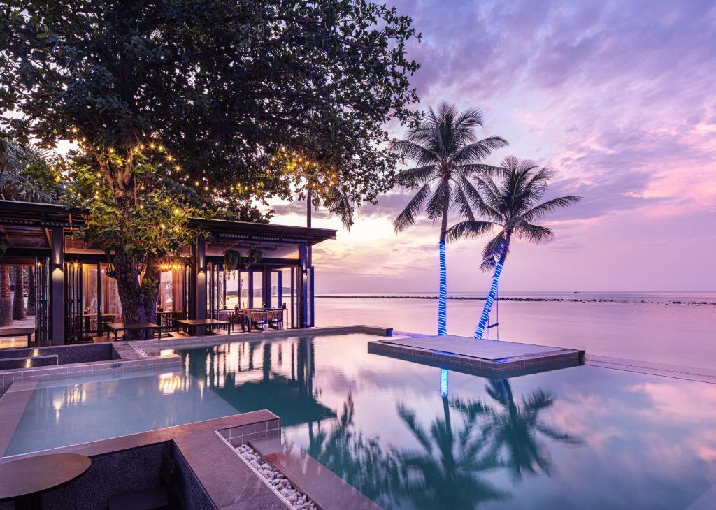 a pool with two palm trees and a house at Lub d Koh Samui Chaweng Beach in Chaweng