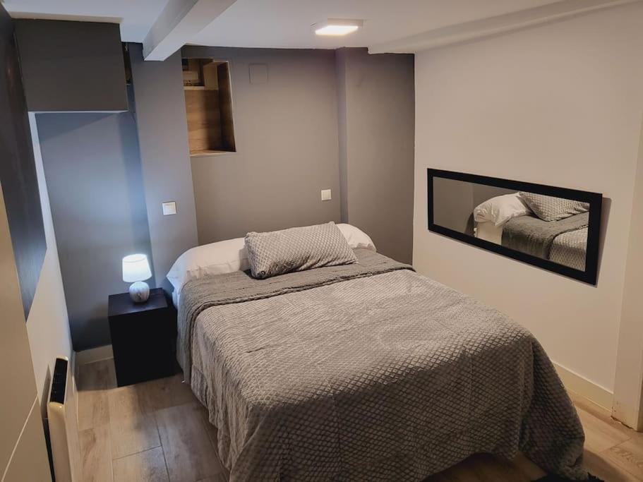 a small bedroom with a bed and a mirror at Precioso apartamento de 2 habitaciones. in Madrid