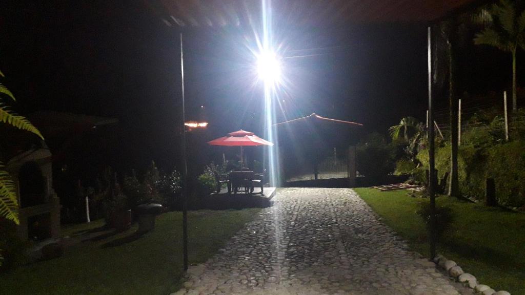 eine Straßenbeleuchtung in der Nacht mit einem Tisch und einem Regenschirm in der Unterkunft Casa rural o chalet in Santa Rosa de Cabal