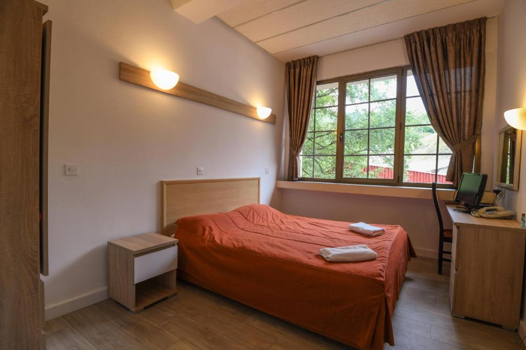 a bedroom with a red bed and a window at Hotel Fersped in Mavrovo