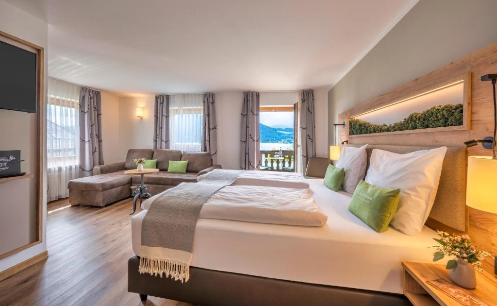 a bedroom with a large bed and a living room at Seehotel zur Post in Tegernsee