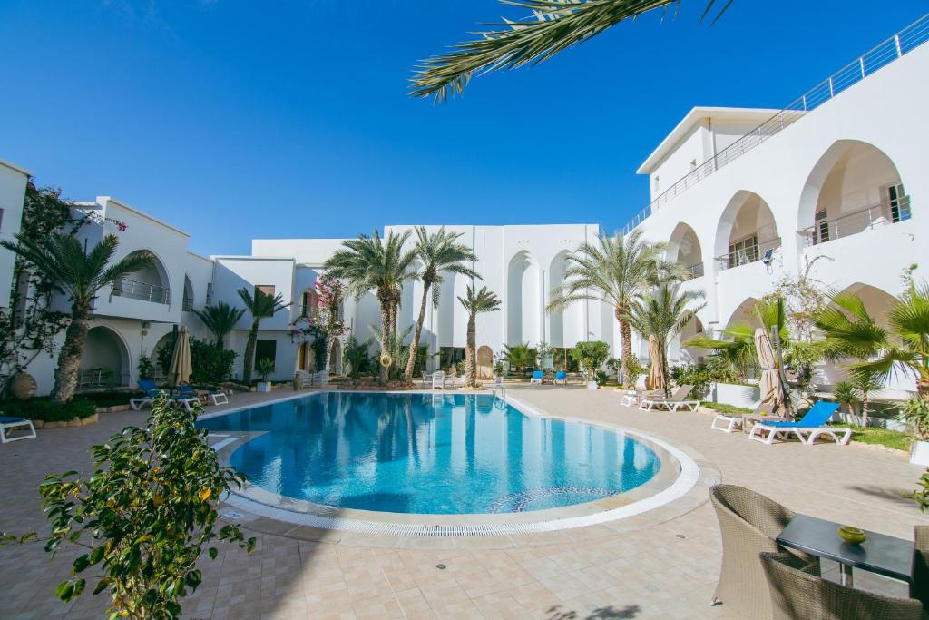 una piscina en el patio de un hotel con palmeras en Palm Djerba Suites en Mezraya