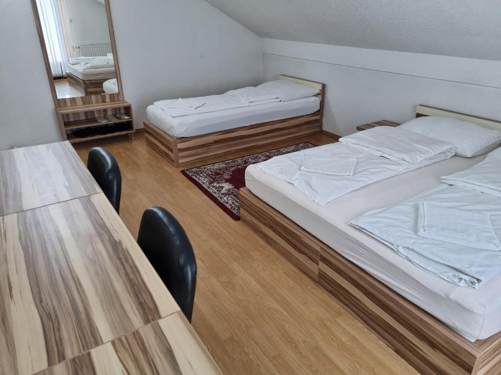 2 Betten in einem Zimmer mit Tisch und Stühlen in der Unterkunft City Bridge Guest House in Bihać