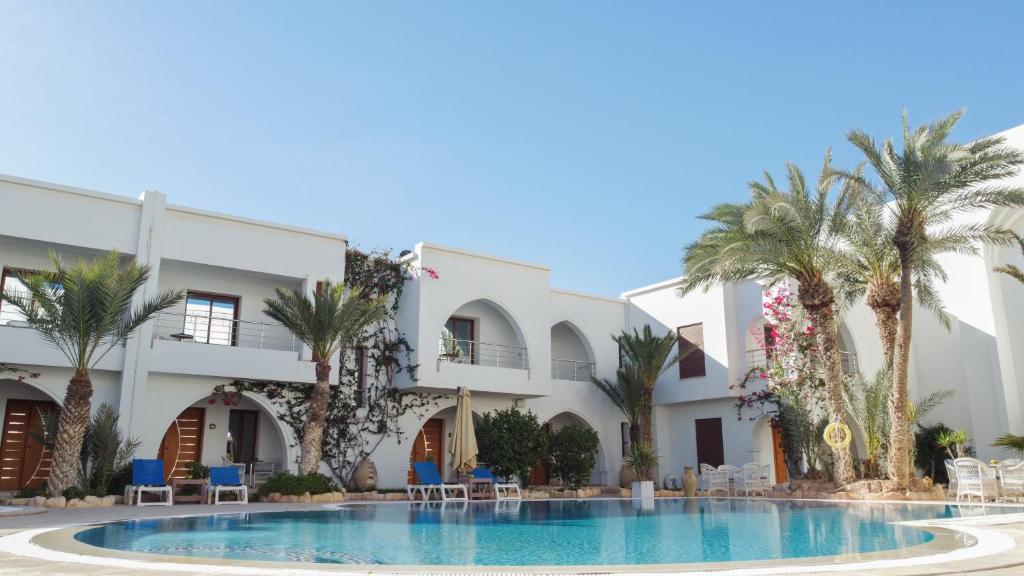 a hotel with a swimming pool and palm trees at Palm Djerba Suites in Mezraya