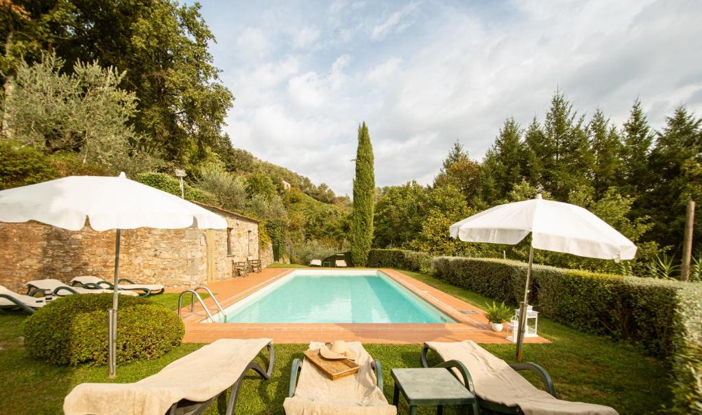 una piscina con sillas y sombrillas en un patio en Casetta di Butia, Mimosa Apartment, en Borgo a Mozzano