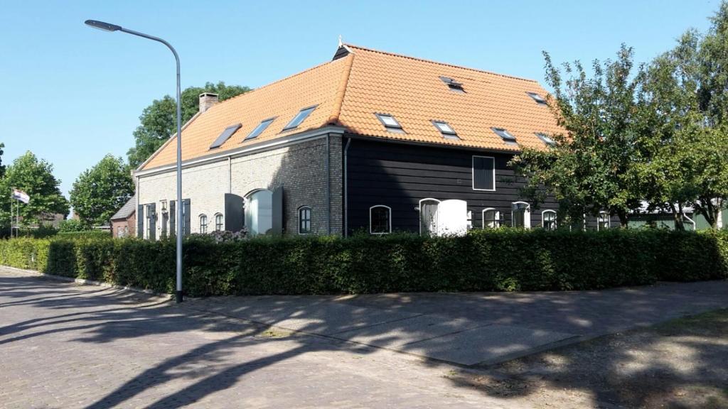 una casa con techo naranja en una calle en De Dorsvloer, en Drimmelen