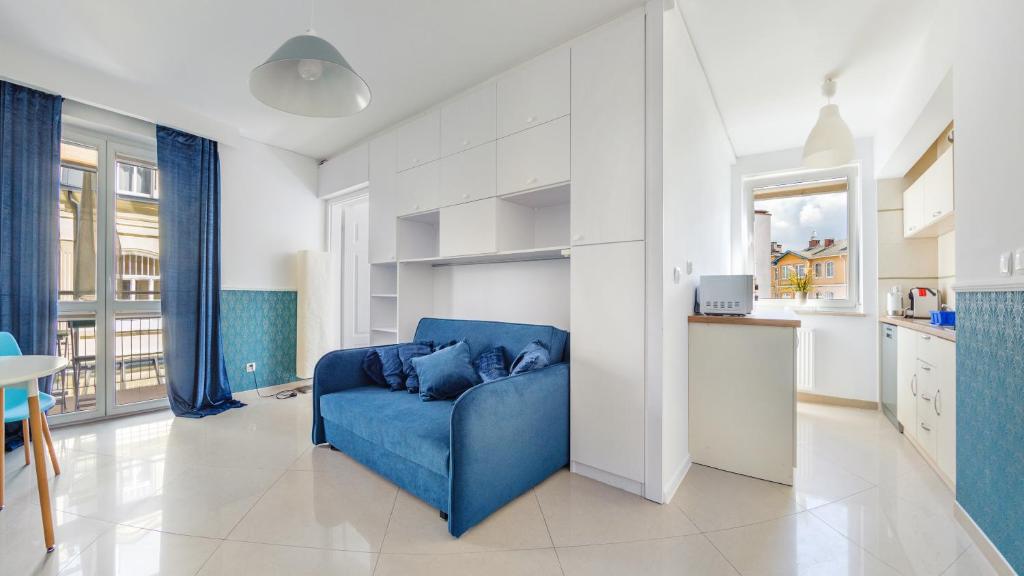 sala de estar con sofá azul y cocina en Apartamenty Sun & Snow Mare Promenada en Międzyzdroje
