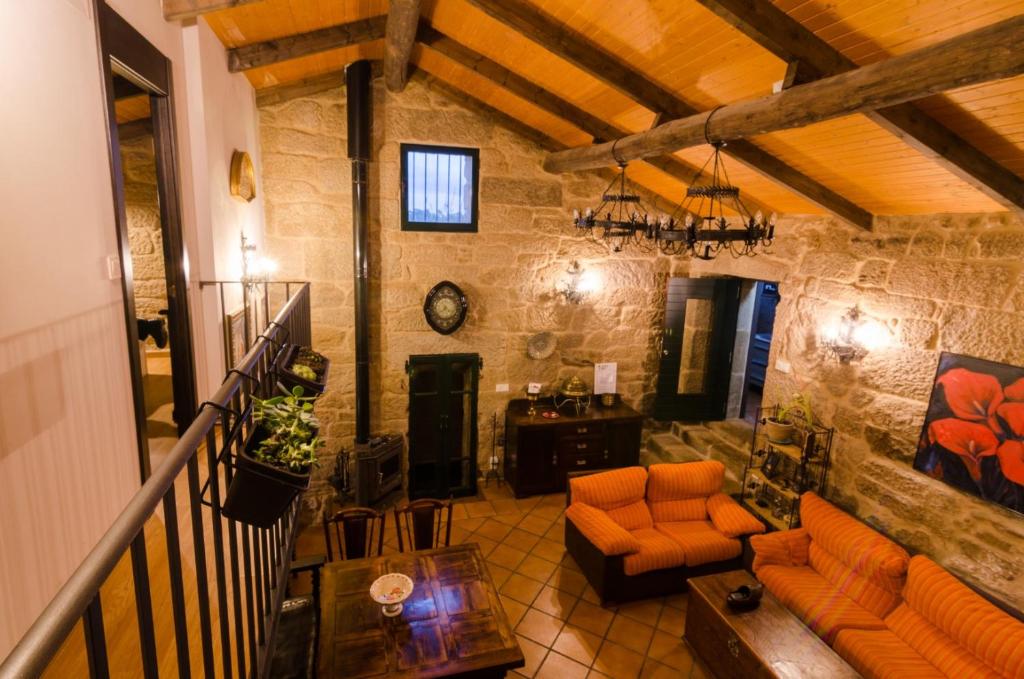 sala de estar con muebles de color naranja y pared de piedra. en A casa da Ita, en Ourense