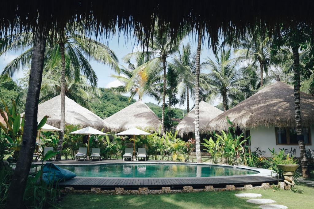 a swimming pool in front of a resort with palm trees at Mana Eco Retreat in Kuta Lombok