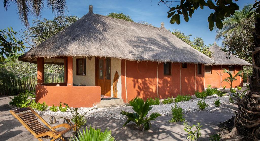 Dinouar的住宿－Bégué Lodge，一座带茅草屋顶的橙色小房子