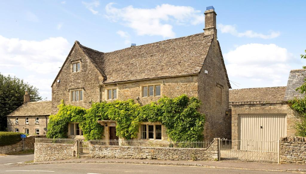 an old stone house with a garage at Green Farm House in Cirencester