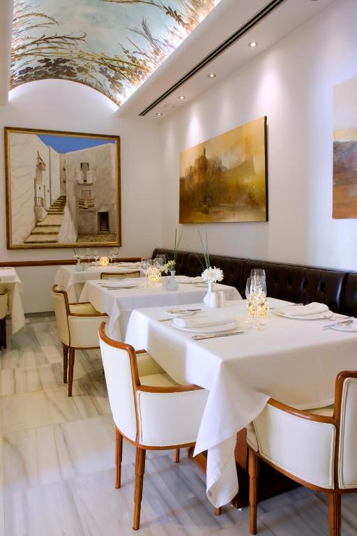 a restaurant with white tables and chairs and a ceiling at Mirador de Dalt Vila-Relais & Chateaux in Ibiza Town