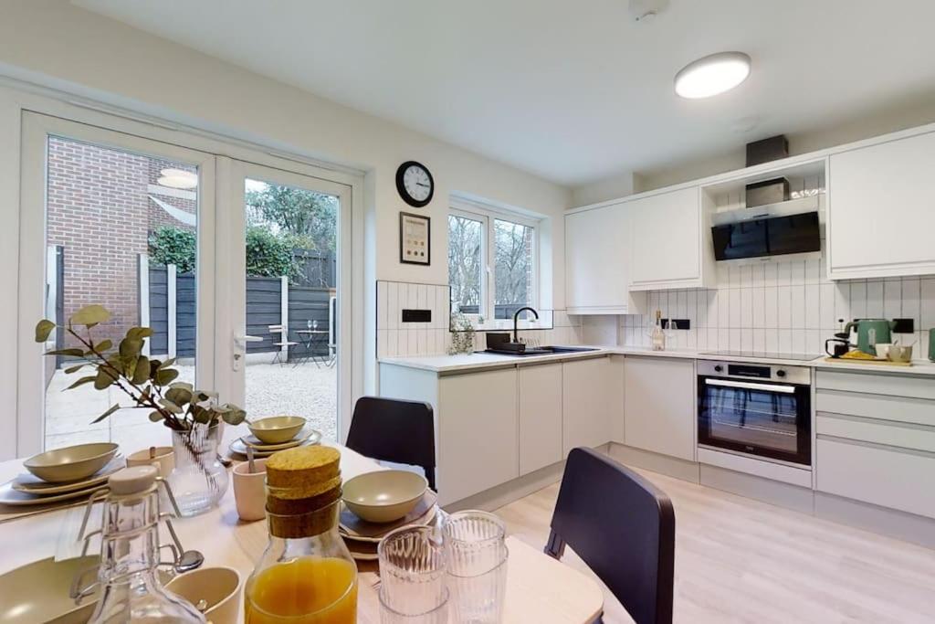 a kitchen with a dining table and a kitchen with white cabinets at Oakwell View - Modern 3 Bed Home in Barnsley