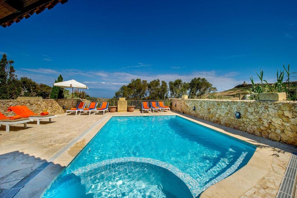 una piscina in una villa con un muro in pietra di Ta Gananz Holiday Home a Għasri