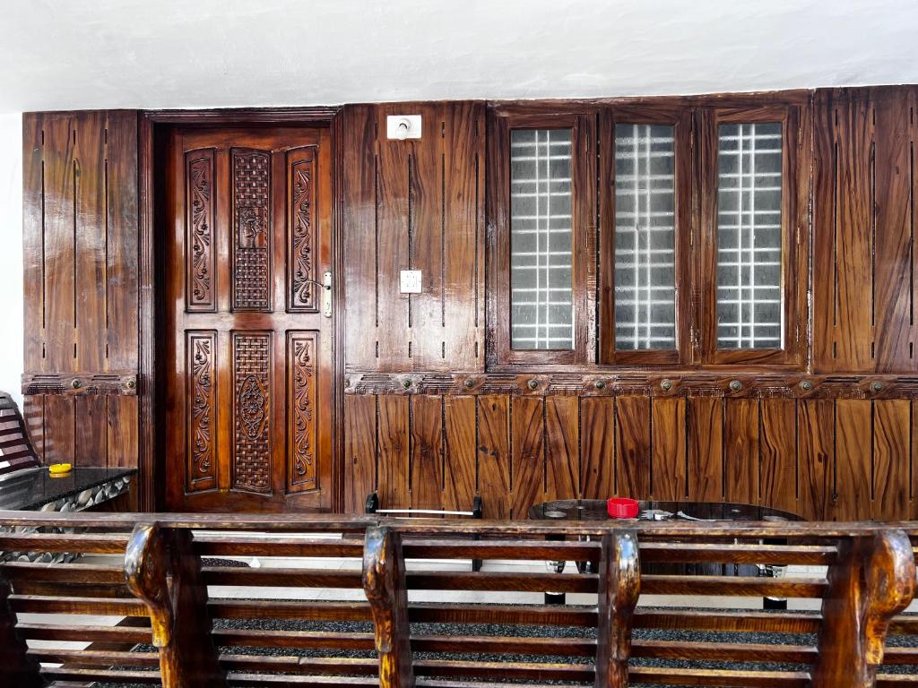 a wooden building with two windows and a wooden bench at Hammock Beach Home in Alleppey