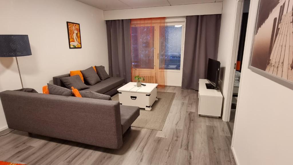 a living room with a couch and a tv at Hamina Orange Apartments Ilves in Hamina