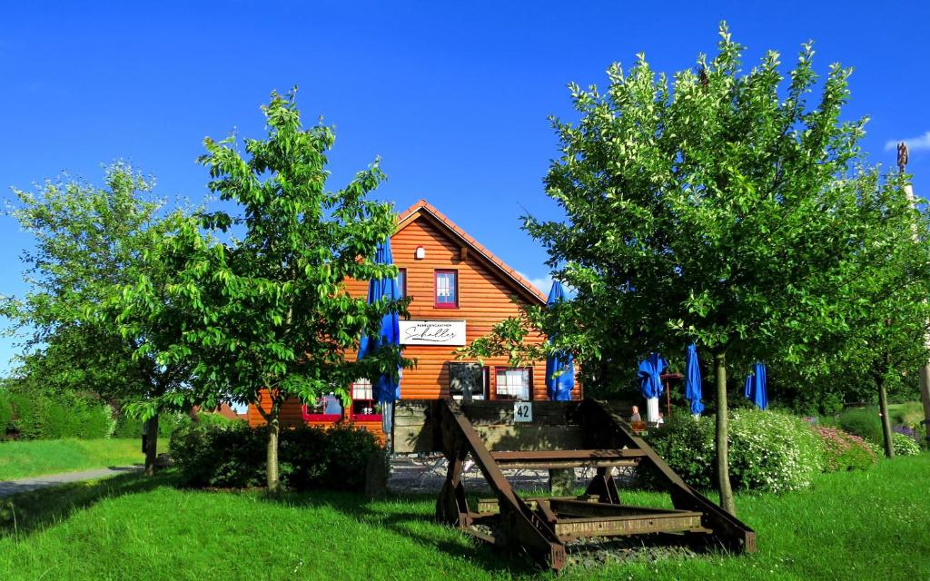 ein Holzhaus mit zwei Bäumen davor in der Unterkunft Familiengasthof Schaller in Floß