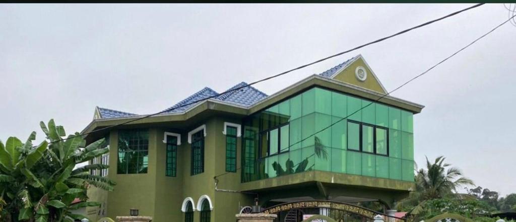 un bâtiment vert avec un toit bleu dans l'établissement Sobey Laris Homestay SWIMMING SALOR, à Kota Bharu