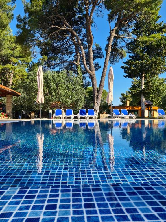 a pool at a resort with chairs and umbrellas at Mediterranean Village San Antonio in Biograd na Moru