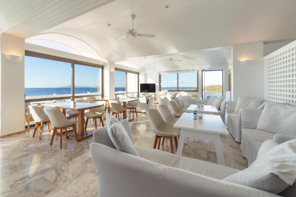 a room with white couches and tables and windows at Hotel Perrakis in Kipri