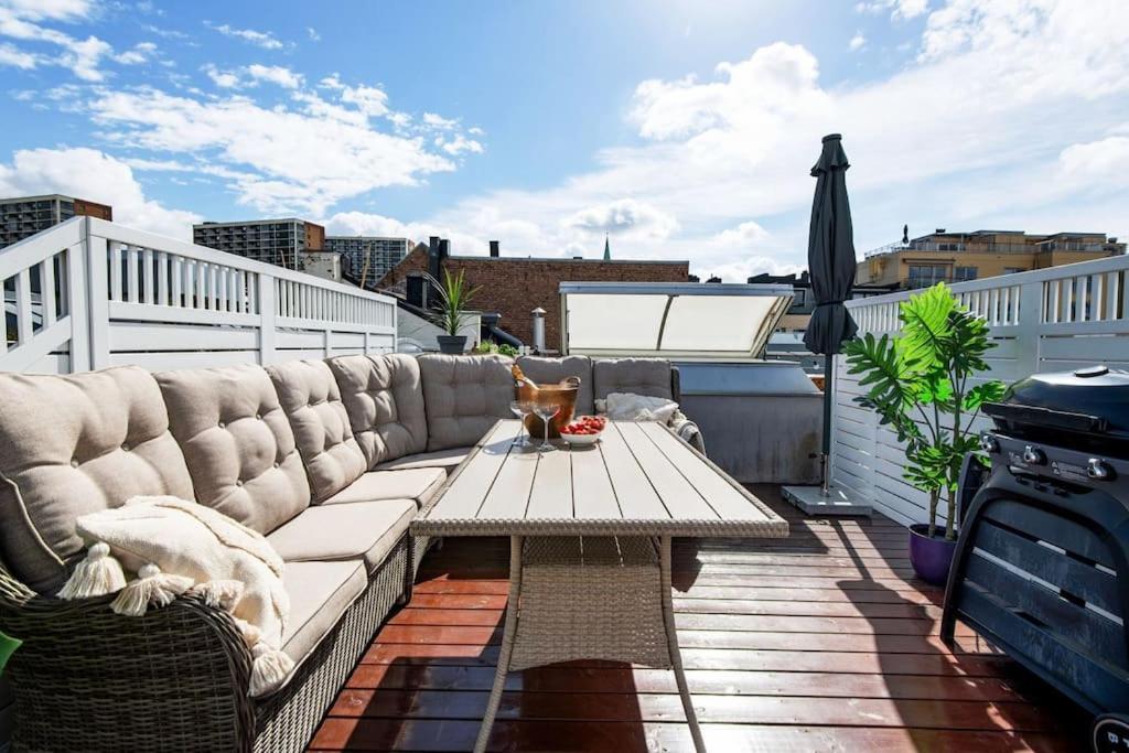 a patio with a couch and a table on a balcony at Live on the roof of Oslo city center in Oslo