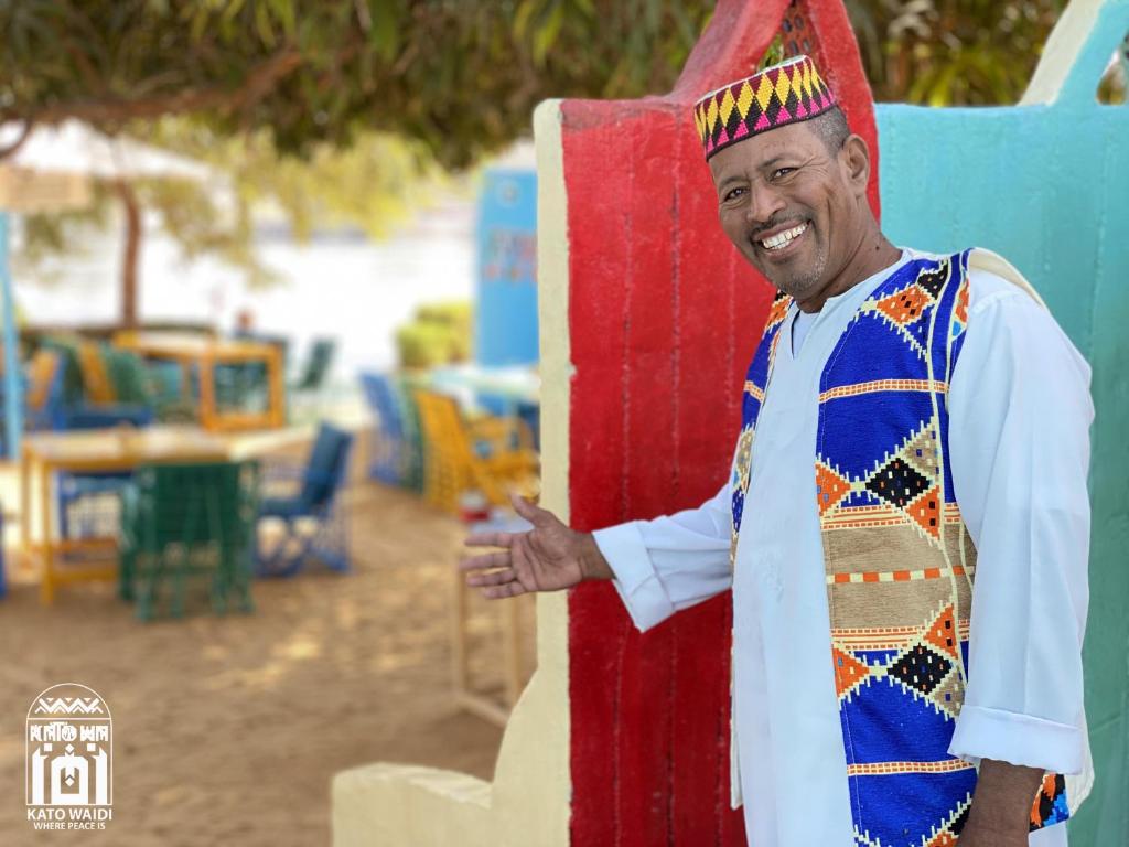 un homme habillé d'un costume indien tenant une planche de surf dans l'établissement Kato Waidi Nubian Resort, à Assouan