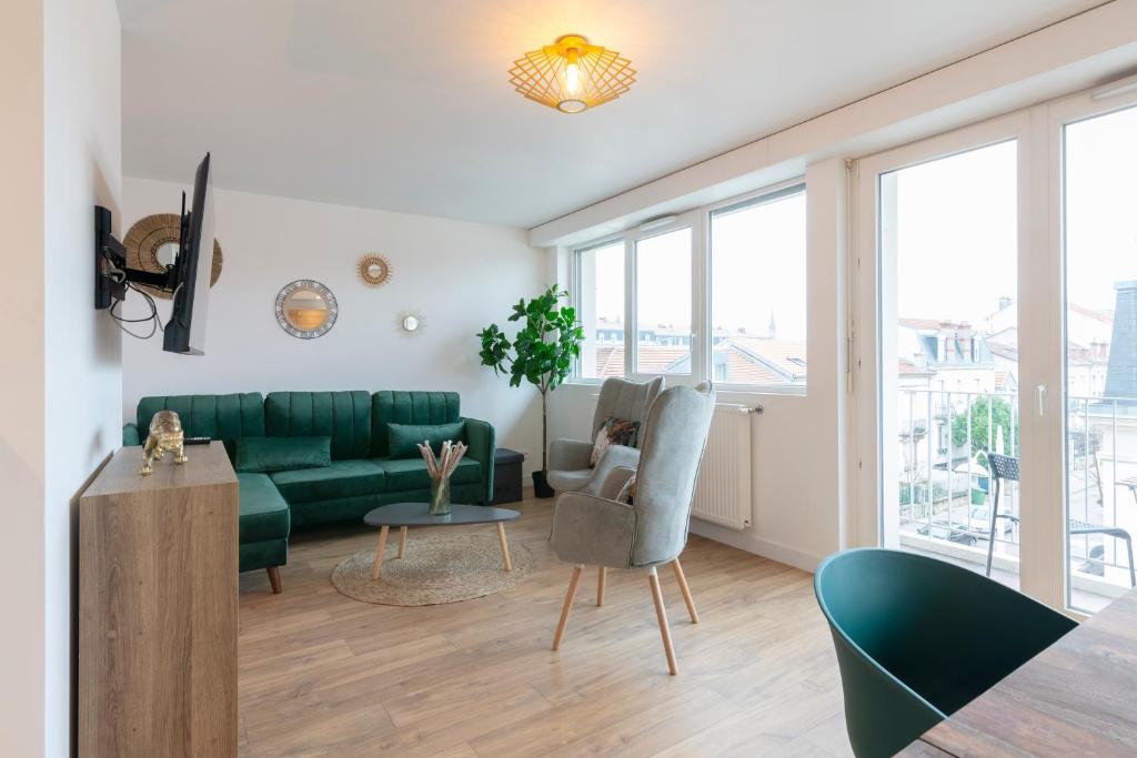 ein Wohnzimmer mit einem grünen Sofa und Stühlen in der Unterkunft Le Placieux avec parking privé in Nancy