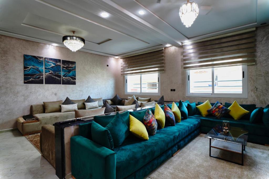 uma sala de estar com um sofá verde e almofadas amarelas em Appartement moderne quartier calme em Fez