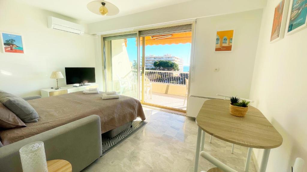 a bedroom with a bed and a table and a balcony at La Couronne du Cros in Cagnes-sur-Mer