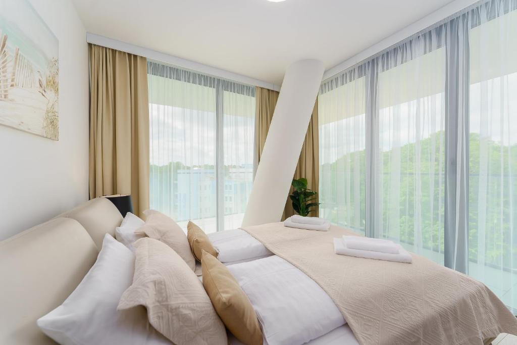 Sea Waves Apartament Resort & SPA 428B by Renters في مينززدرويه: غرفة نوم بسرير كبير ونوافذ كبيرة