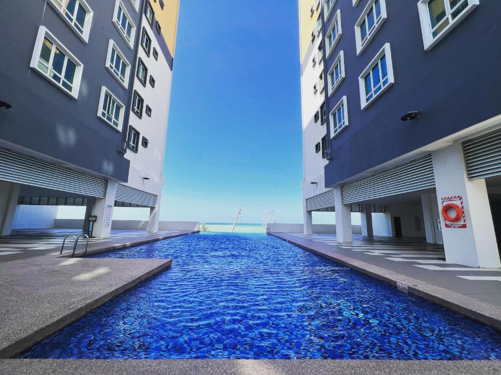 una piscina entre dos edificios con agua azul entre ellos en Ureshii Homestay Ladang Tanjung Kuala Terengganu with POOL, en Kuala Terengganu