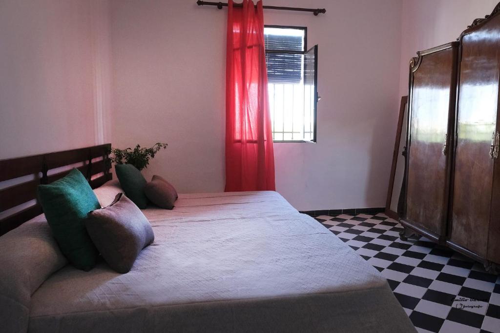 ALOJAMIENTO RURAL CASA LOS ARENALES في قرطبة: غرفة نوم بسرير كبير وستارة حمراء