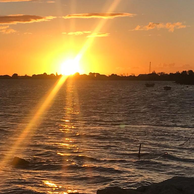 un coucher de soleil sur un plan d'eau avec le soleil couchant dans l'établissement LA CASA SANILLS, à Saint-Hippolyte