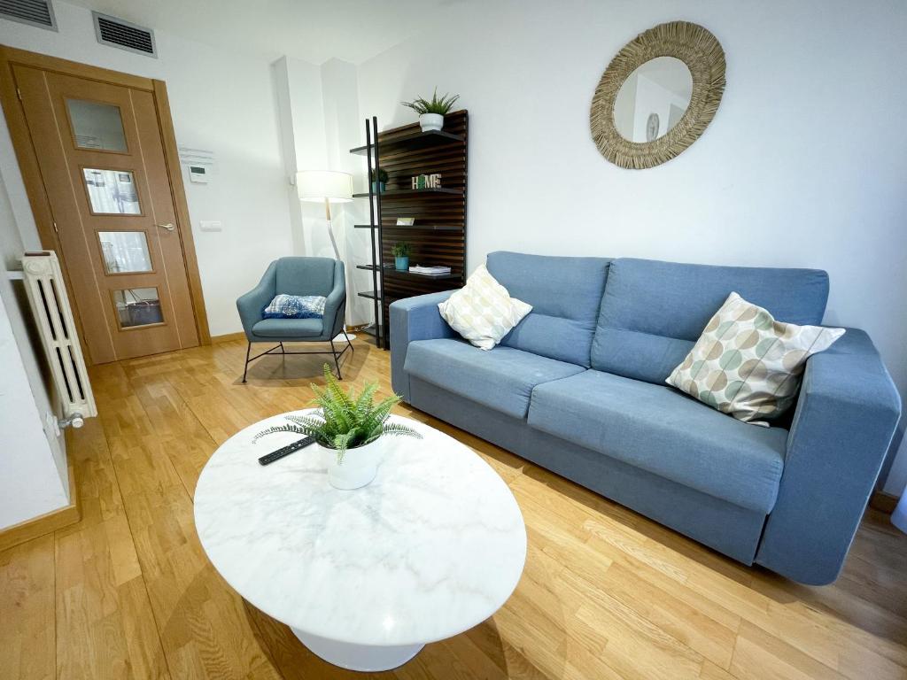 ein Wohnzimmer mit einem blauen Sofa und einem Tisch in der Unterkunft AZ El Balcón de San Felipe in Saragossa