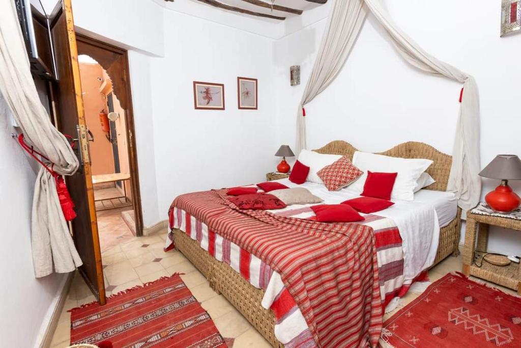 une chambre avec un grand lit avec des oreillers rouges dans l'établissement Riad Aquarelle By GE, à Marrakech