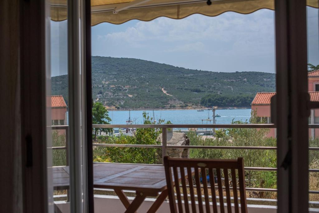 a window with a table and a view of a lake at Apartman Marenic in Cres