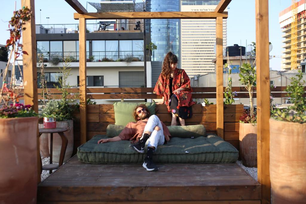 un homme est assis sur un canapé sur un toit dans l'établissement Rena's House, à Tel Aviv