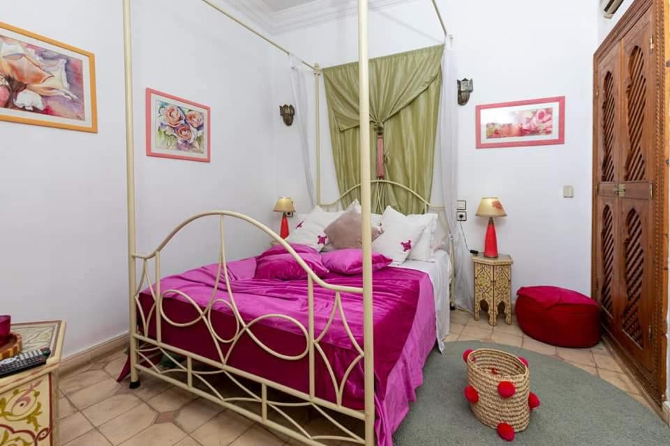 1 dormitorio con cama con dosel y sábanas moradas en Riad Aquarelle By GE en Marrakech