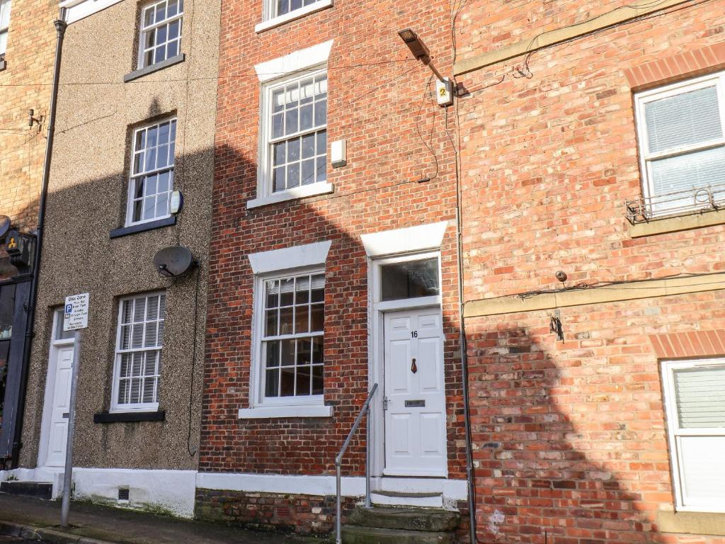 um edifício de tijolos com uma porta branca e janelas em 16 St Sepulchre Street em Scarborough