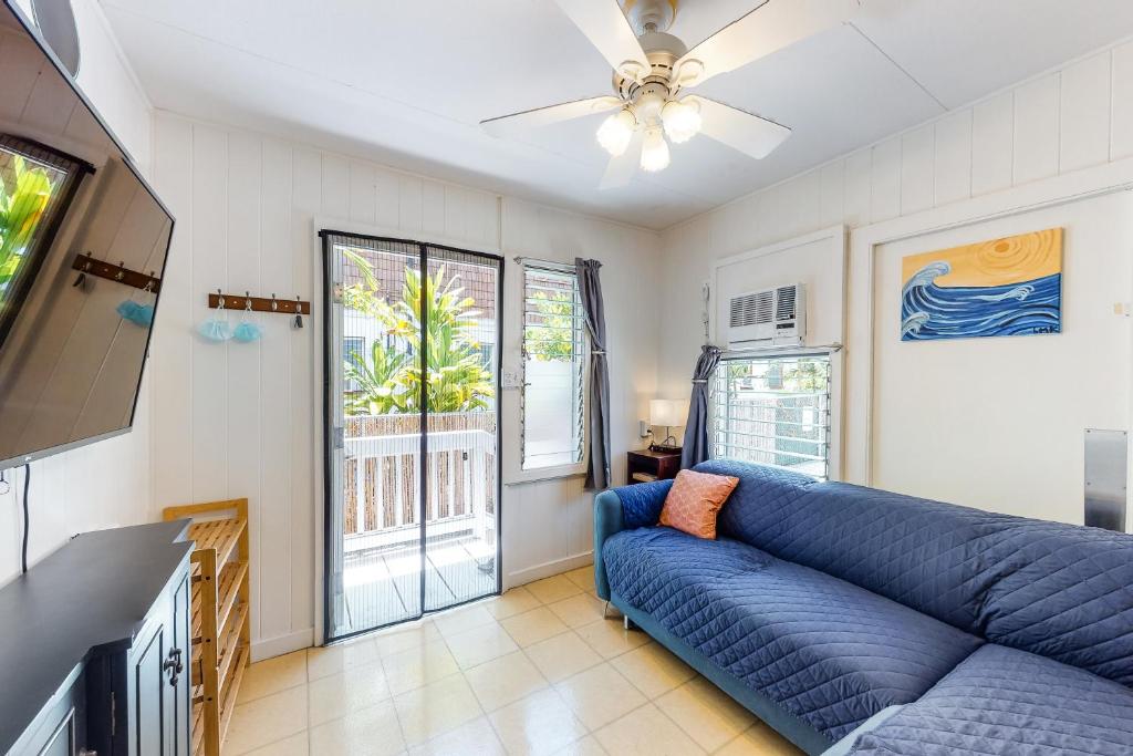 ein Wohnzimmer mit einem blauen Sofa und einem TV in der Unterkunft Monsarrat Apt D - 30-Night Minimum in Honolulu