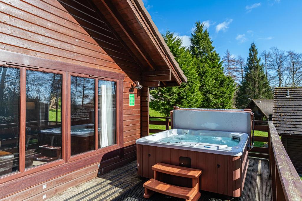 uma banheira de hidromassagem num deque ao lado de uma casa em Lady Galloway 28 with Hot Tub em Newton Stewart