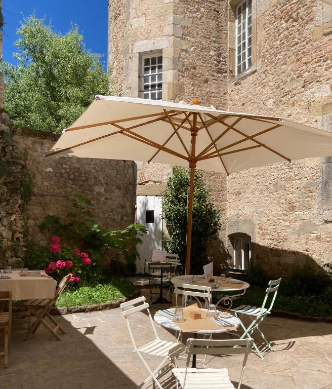 une terrasse avec un parasol, des tables et des chaises dans l'établissement Le Cocand, à Autun
