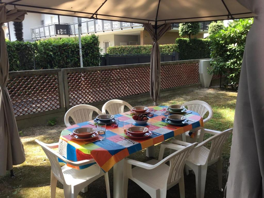 リニャーノ・サッビアドーロにあるVilla Luciaのテーブルと椅子、カラフルなテーブルとパラソル付