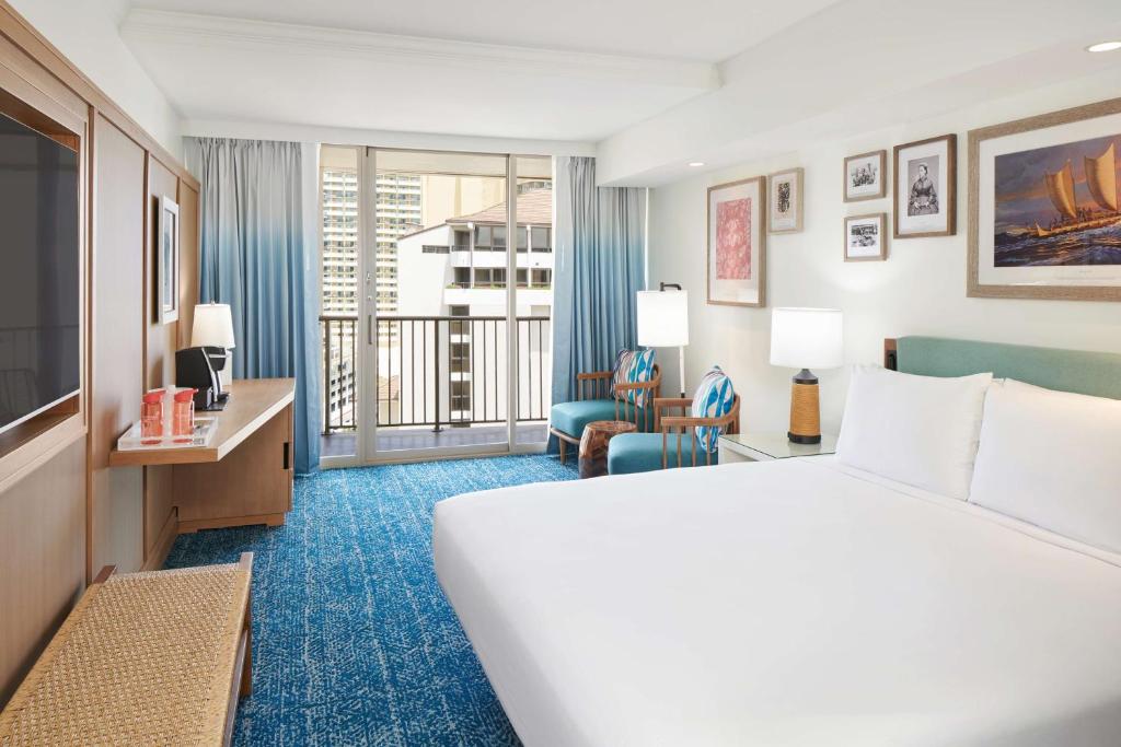 a hotel room with a bed and a balcony at Outrigger Reef Waikiki Beach Resort in Honolulu