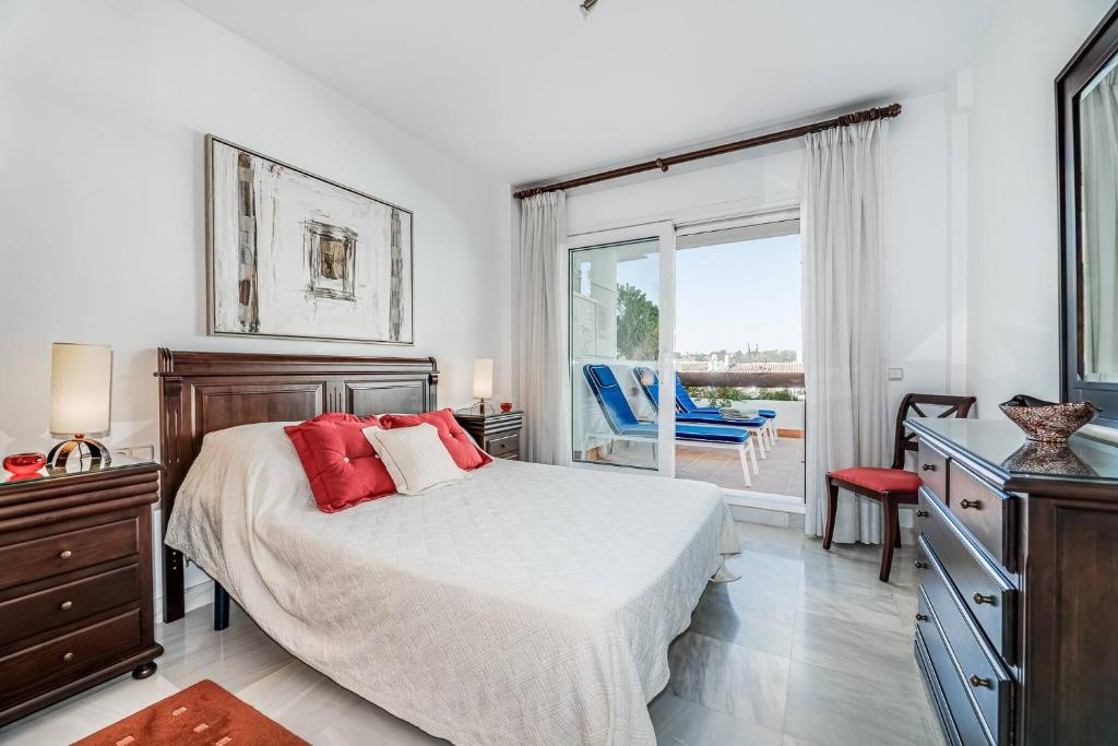 1 dormitorio con 1 cama con almohadas rojas y balcón en Great Location, Spacious And Beautiful Apartment, en Marbella