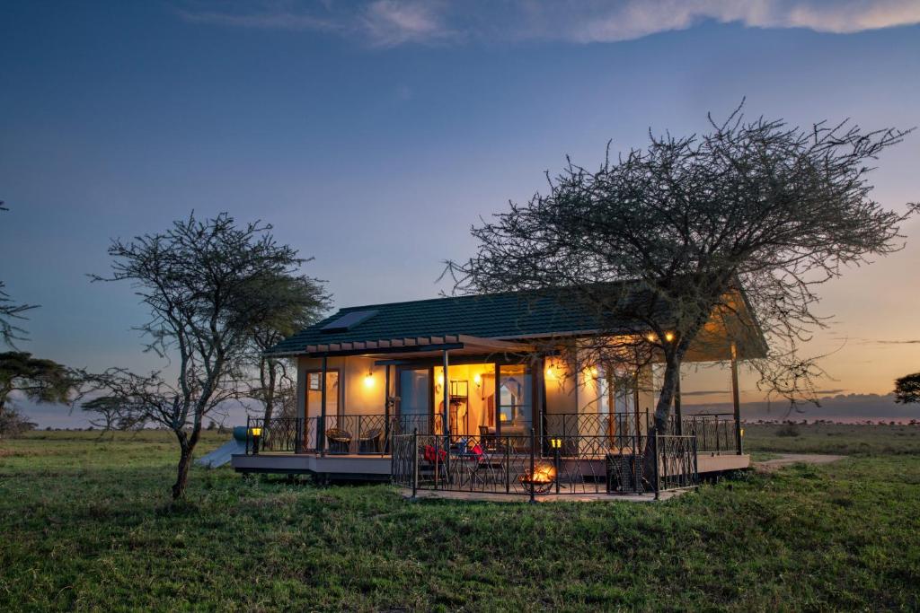 a small house with a green roof in a field at Serengeti Sametu Camp in Serengeti National Park