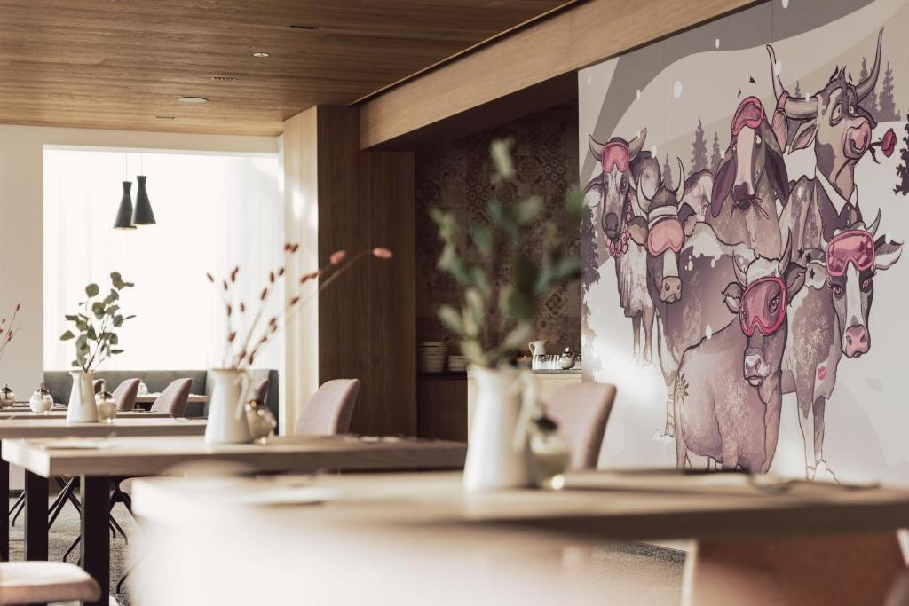 una fila di tavoli in un ristorante con un murale di Hotel Lisl - Alpine Comfort a Kühtai