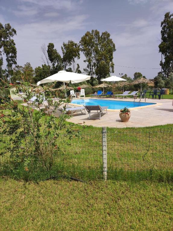 een hek rond een zwembad met parasols bij Agriturismo Su Niu in Uta